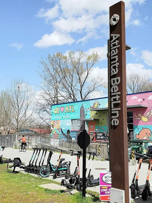 Vibrant scene on the Atlanta BeltLine featuring colorful murals and electric scooters under a clear blue sky.