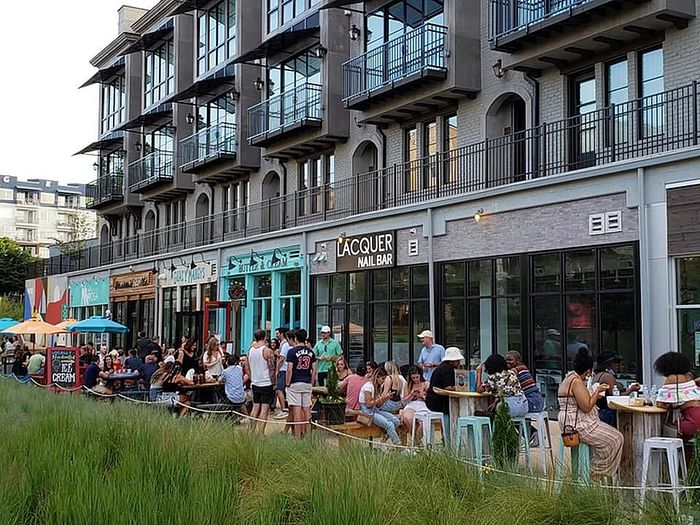 Vibrant urban building showcasing trendy shops and cafes with lively outdoor seating and modern architecture.