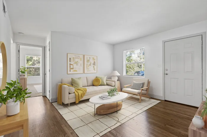 Bright and inviting living room with elegant decor, featuring a cozy sofa, stylish armchair, and natural wood flooring.