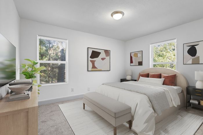 Bright and inviting bedroom with modern decor, featuring a cozy bed, abstract wall art, and large windows letting in natural light.