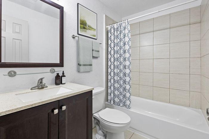 Modern bathroom design featuring sleek dark wood vanity, elegant countertop, and stylish patterned shower curtain.