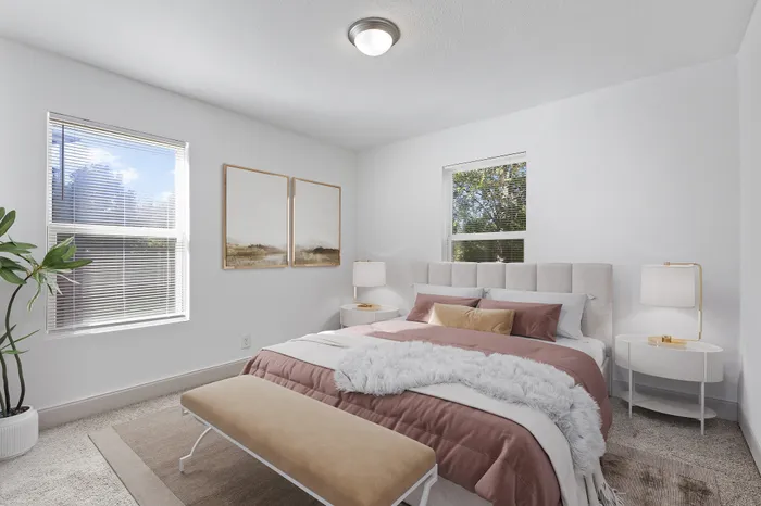 Bright and elegant bedroom featuring a plush bed with soft furnishings, large window illuminating the space, and modern decor accents for a serene ambiance.
