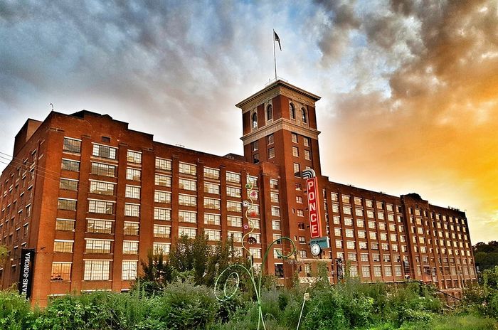 Iconic brick building with tall windows and a vintage-style tower, bathed in the warm glow of sunset, showcasing urban charm and historic elegance.
