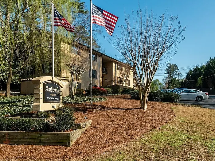 Charming Amberidge apartment community showcased with lush landscaping and patriotic flags in a serene setting.