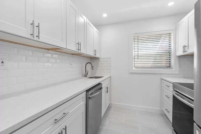 Sleek and modern kitchen with bright white cabinetry, elegant subway tile backsplash, and stainless steel appliances.