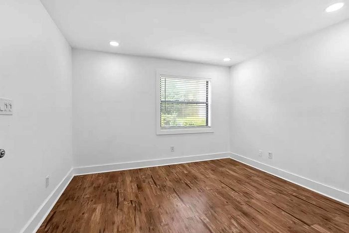 Bright, spacious room featuring elegant wood flooring and a large window, perfect for a serene ambiance.