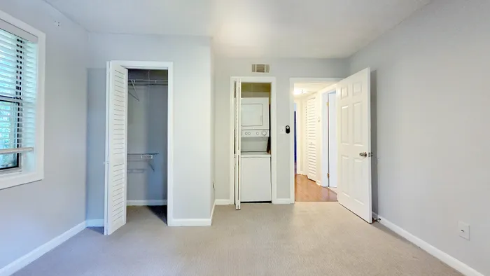 Bright and airy bedroom with a spacious closet and in-unit washer dryer, featuring soft carpet and modern finishes.