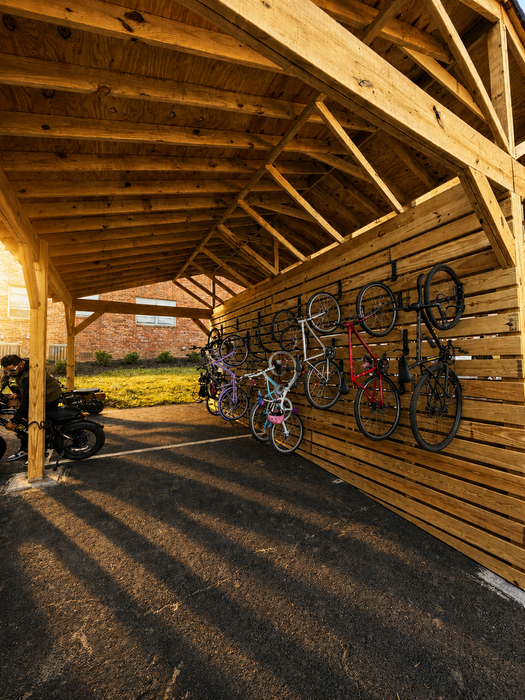 Inviting wooden bike storage shed showcasing convenient vertical racks, bathed in warm sunlight, perfect for an active lifestyle.
