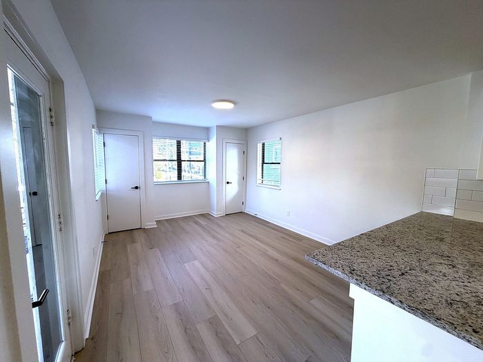 Bright, modern living space with elegant hardwood floors, large windows for natural light, and a polished granite countertop.