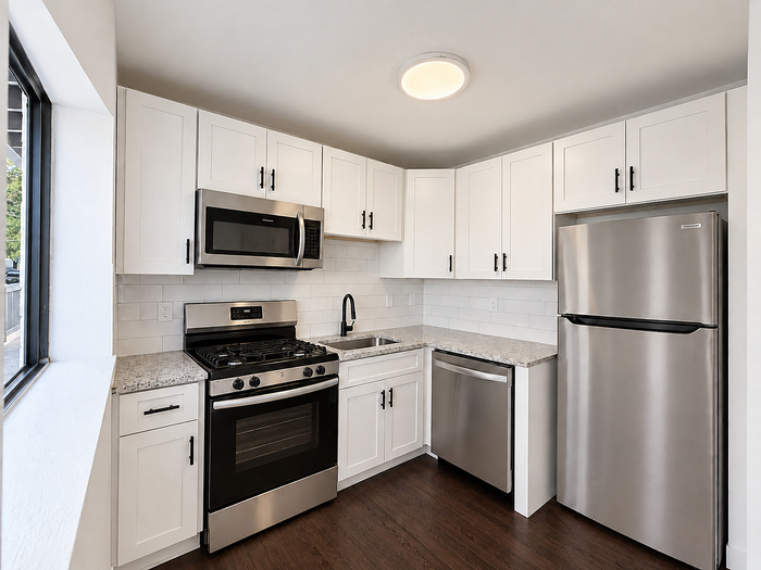 Modern kitchen with sleek stainless steel appliances, white cabinetry, and polished granite countertops, perfect for culinary enthusiasts.