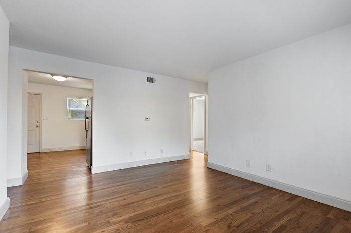 Bright and spacious living area with beautiful hardwood floors, leading to the kitchen and adjacent rooms.