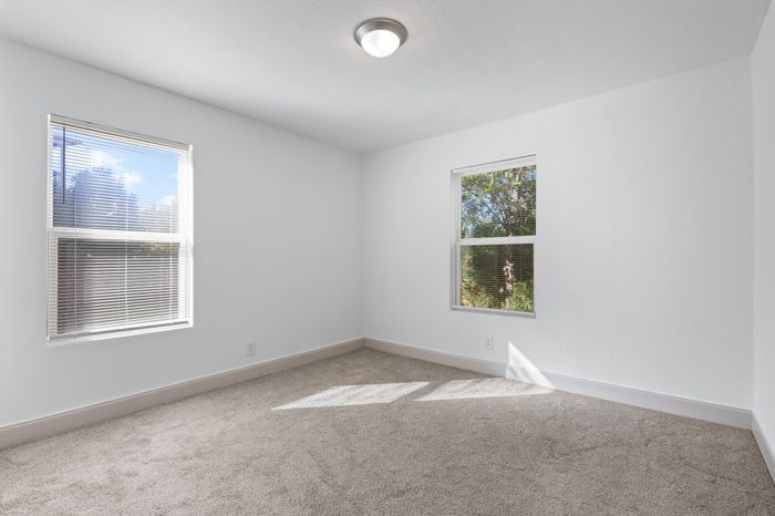 Bright and airy bedroom with plush carpet and large windows offering scenic views.