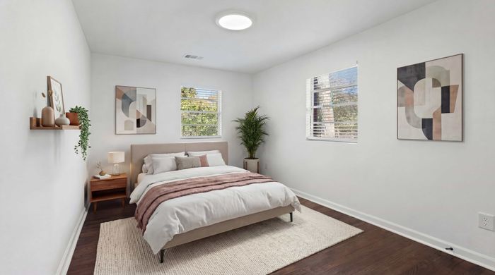 Bright and inviting bedroom featuring a cozy bed with soft linens, elegant wall art, and ample natural light.