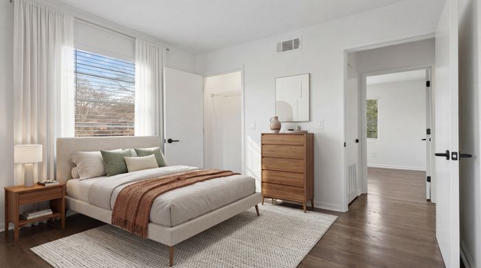 Bright and cozy bedroom with modern decor, featuring a plush bed, wooden dresser, and soft natural light.