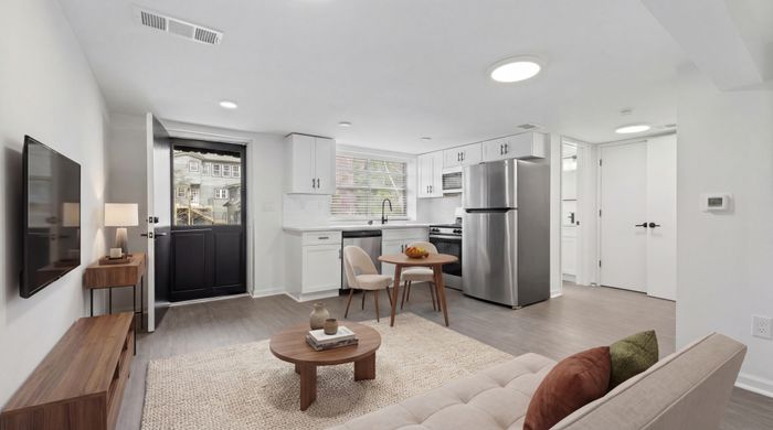 Modern open-concept living space featuring a cozy lounge area and elegant kitchen with stainless steel appliances.