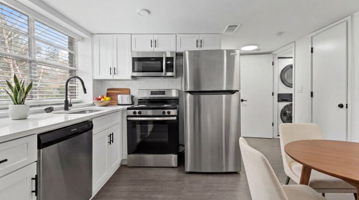 Modern kitchen with stainless steel appliances, elegant white cabinetry, and a cozy dining area.