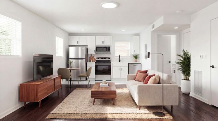 Modern open-plan living area featuring sleek kitchen, cozy sofa, and stylish wooden furniture with natural light streaming through large windows.