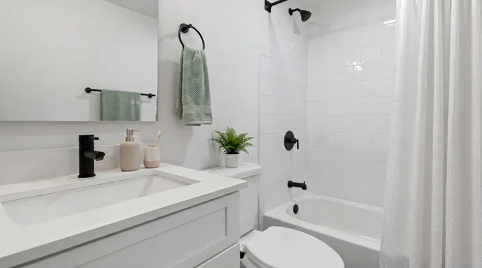Modern bathroom with sleek white vanity, stylish black fixtures, and elegant shower area.