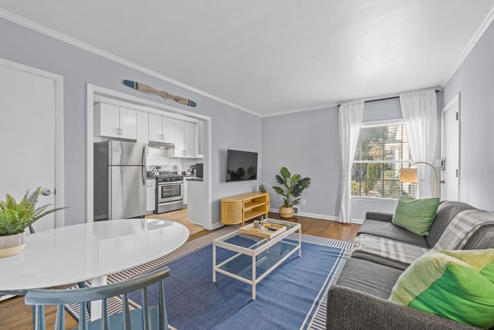 Contemporary living room with open-concept kitchen, featuring sleek stainless steel appliances, cozy seating area, and large windows for natural light.