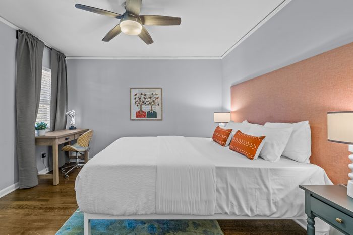 Modern bedroom with cozy king-size bed, stylish artwork above the headboard, and a chic workspace with natural light.