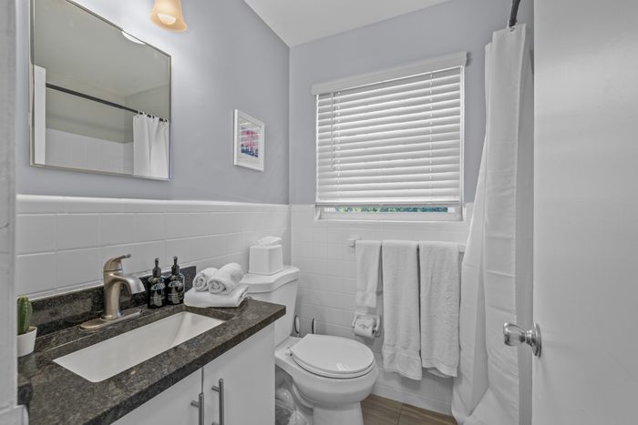 Elegant bathroom with a modern sink, sleek countertop, and natural light filtering through blinds.
