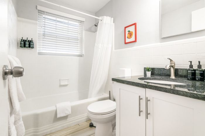 Bright, modern bathroom featuring a sleek vanity, a bathtub with shower, and elegant white tiles creating a fresh and inviting atmosphere.