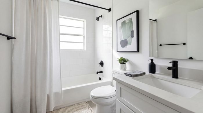 Elegant bathroom with white tiles, modern black fixtures, and stylish artwork, offering a serene and refreshing atmosphere.