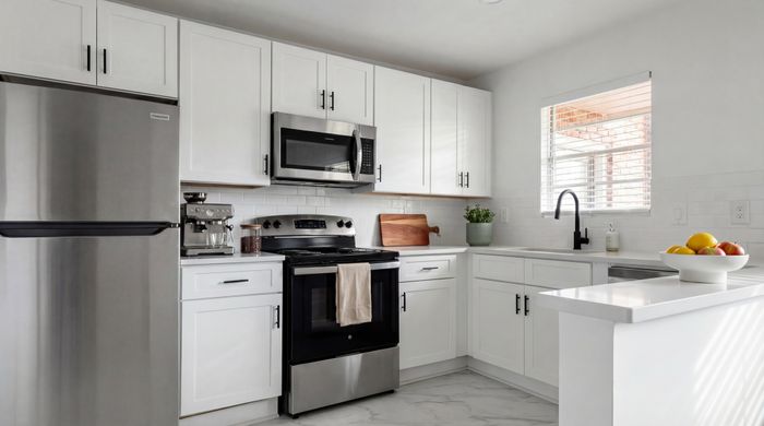 Modern kitchen with sleek stainless steel appliances, white cabinetry, and elegant countertops.