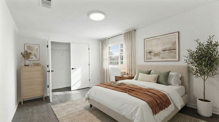 Bright and cozy bedroom with modern decor, featuring a plush bed, stylish dresser, and elegant indoor plant.