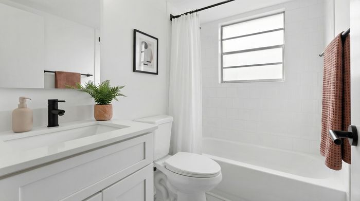 Contemporary bathroom with sleek white vanity, modern black fixtures, and bright natural lighting.