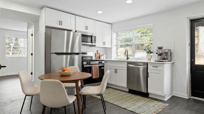 Bright and modern kitchen with sleek appliances, white cabinetry, and a cozy dining area with a round table.
