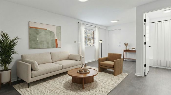 Bright and modern living room featuring a beige sofa, stylish armchair, and contemporary artwork on the wall, complemented by natural light from large windows.