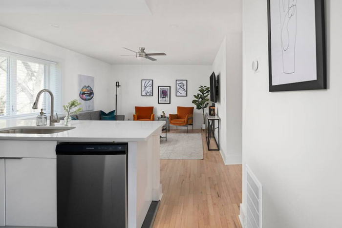 Chic open-concept living area with modern kitchen, stylish decor, and natural hardwood flooring.