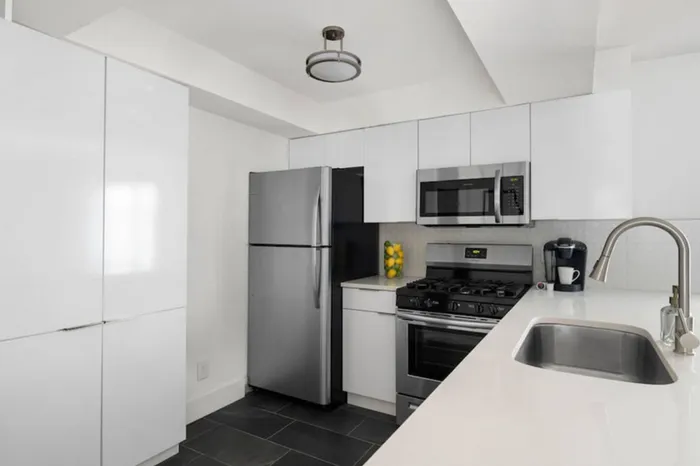 Modern kitchen featuring sleek white cabinets, stainless steel appliances, and a chic tile backsplash.