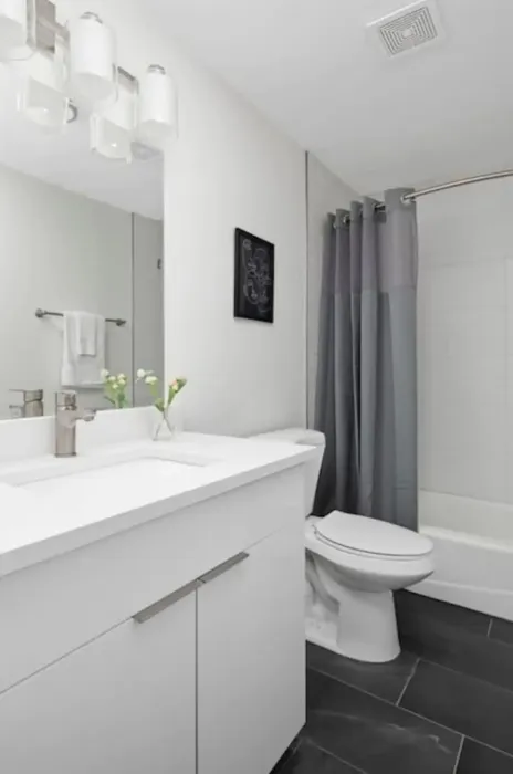 Sleek modern bathroom with a white vanity, elegant lighting, and stylish shower curtain.