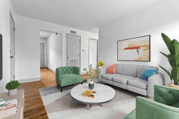 Inviting living room with modern decor, featuring a comfortable gray sofa, stylish green chairs, and a chic marble coffee table.