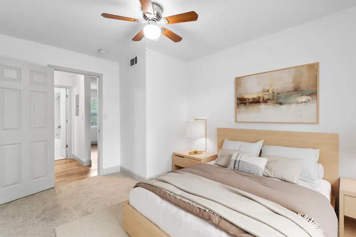 Bright and cozy bedroom featuring a comfortable bed with neutral tones, stylish decor, and a ceiling fan for added comfort.