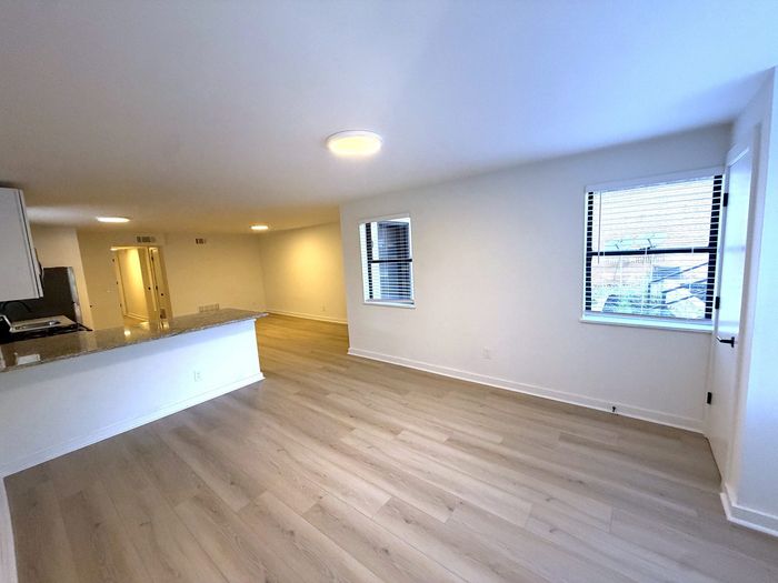 Inviting open-concept living space with sleek hardwood floors, a modern kitchen with granite countertops, and ample natural light.