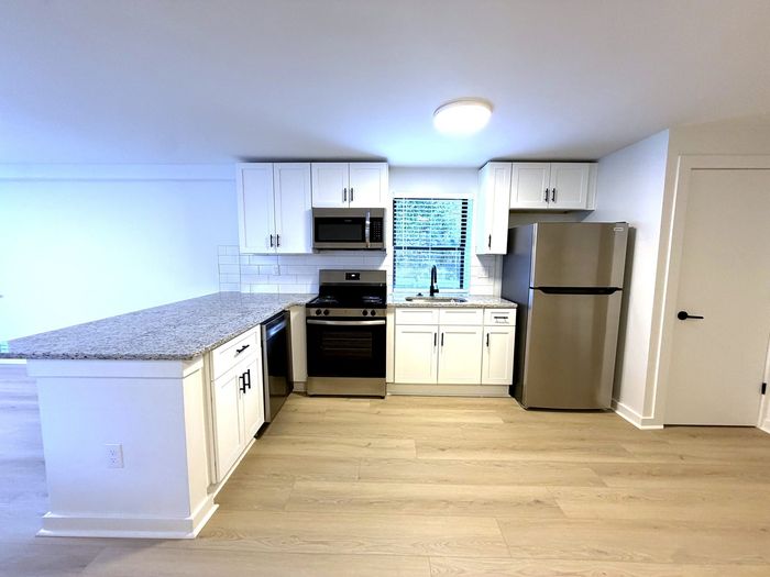 Modern kitchen with sleek stainless steel appliances, elegant white cabinetry, and a granite countertop, creating a bright and inviting space.