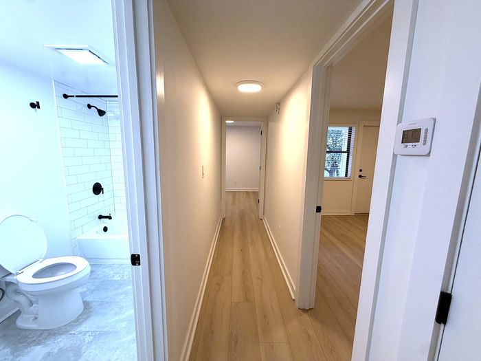 Bright hallway leading to an elegant modern bathroom with sleek fixtures, enhancing the apartment's inviting ambiance.