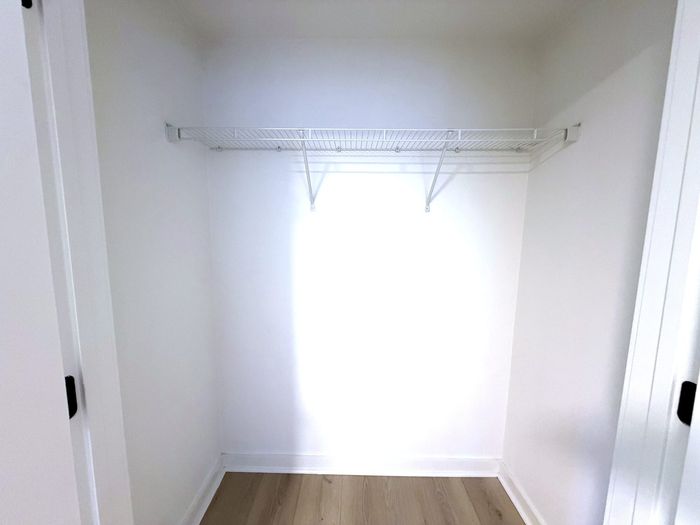 Bright, spacious closet with white shelving and hardwood floors, perfect for organized storage.