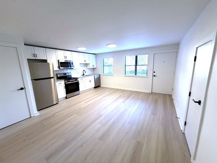 Modern open-plan kitchen with sleek stainless steel appliances, bright white cabinetry, and elegant wood flooring.
