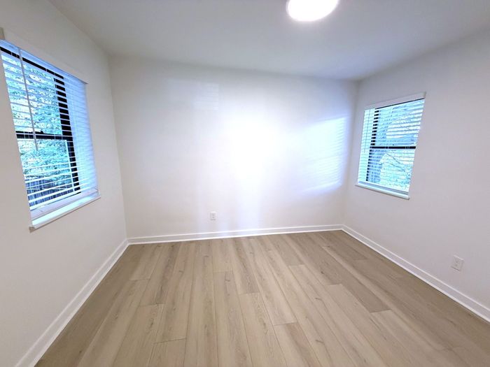Bright and airy empty room with large windows and sleek hardwood flooring, ideal for customizing your living space.