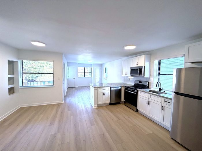 Bright and modern kitchen with sleek stainless steel appliances, elegant white cabinetry, and stunning hardwood floors.