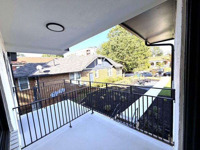 Bright balcony with modern railing offering a serene view of well-maintained garden and residential surroundings.