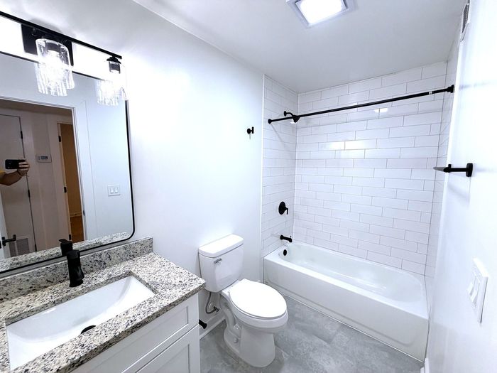 Modern bathroom with elegant granite countertop, sleek white tiles, and stylish black fixtures.