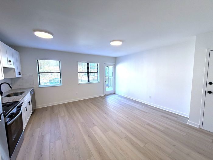 Bright and modern open-plan living area with sleek kitchen, large windows, and elegant wood flooring.