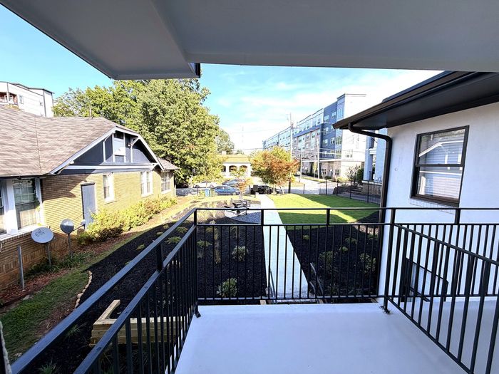 Charming balcony view overlooking landscaped garden and modern apartment complex, offering a blend of classic and contemporary architecture.