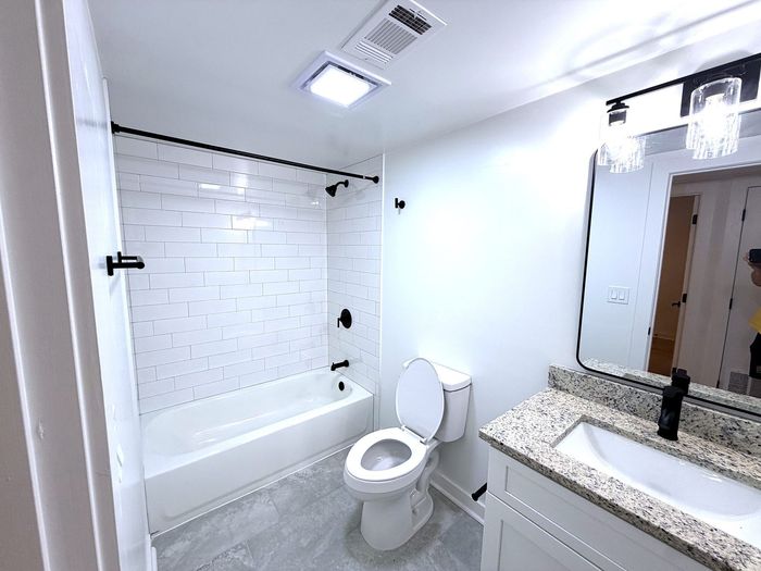 Bright and modern bathroom featuring sleek granite countertops, a chic white vanity, and elegant subway tile in the shower area.