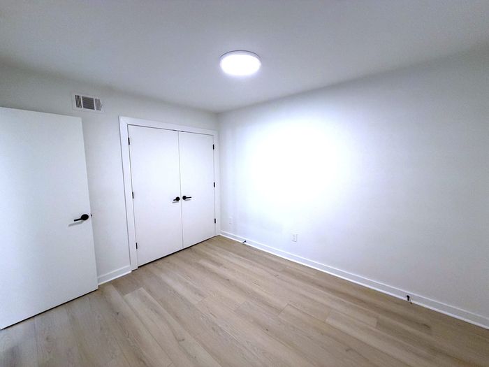 Bright room with sleek hardwood floors and modern white double doors, offering versatile space for a cozy bedroom or home office.
